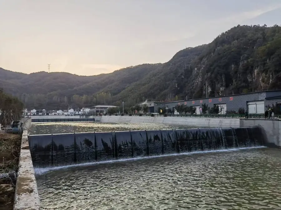 Multi-span dam at dusk with mountain backdrop